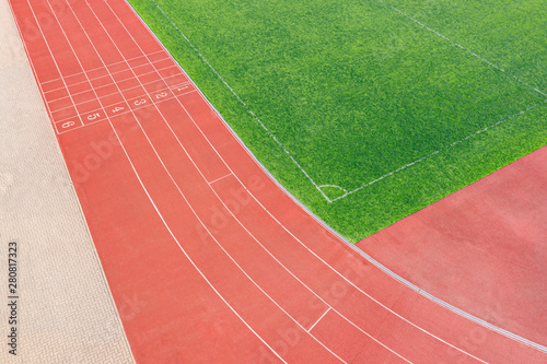 cinder track in athletic stadium and soccer field with artificial green grass