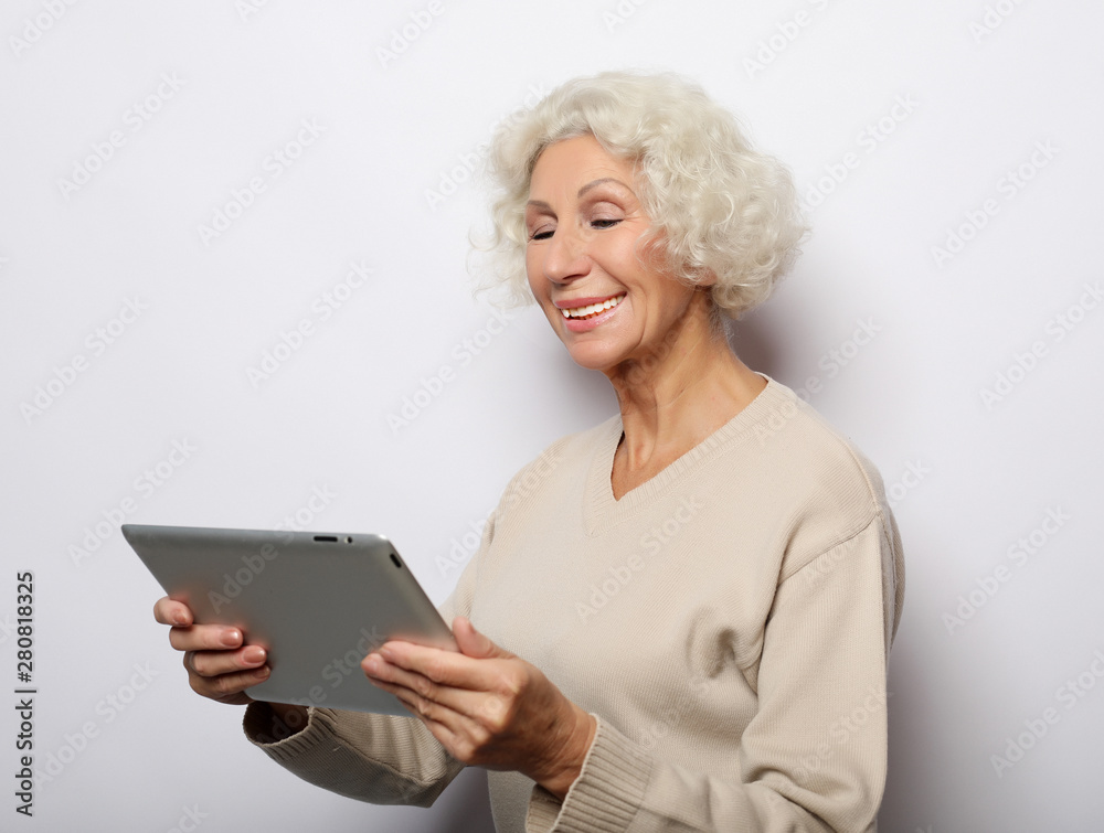 lifestyle, technology and people concept: mature woman using a tablet, communicates with children and grandchildren lifestyle, technology and people concept: mature woman using a tablet, communicates with children and grandchildren