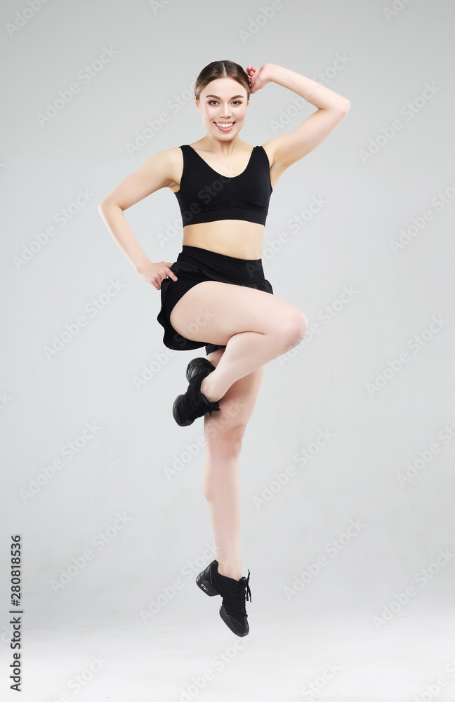 Sport, fitness and people concept: Beautiful young woman dressed in sportswear jumping up over grey background Sport, fitness and people concept: Beautiful young woman dressed in sportswear jumping up over grey background
