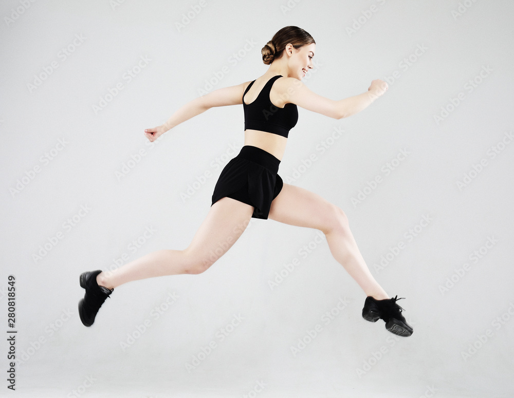 Sport, fitness and people concept: Beautiful young woman dressed in sportswear jumping up over grey background