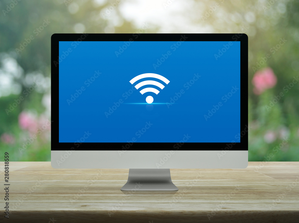 Wi-fi flat icon on desktop modern computer monitor screen on wooden table over blur pink flower and tree in park, Technology internet online concept Wi-fi flat icon on desktop modern computer monitor screen on wooden table over blur pink flower and tree in park, Technology internet online concept