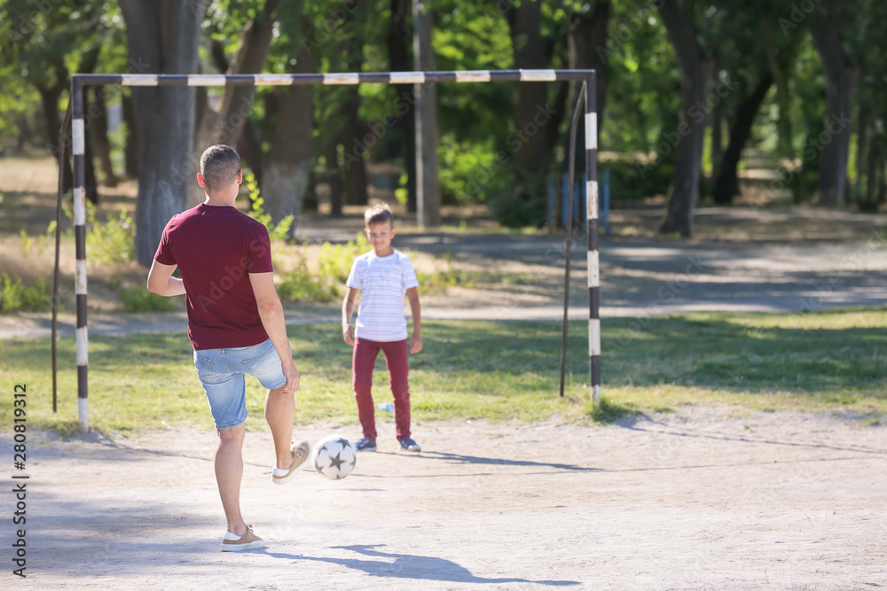 Little boy with his dad playing football on soccer pitch Little boy with his dad playing football on soccer pitch