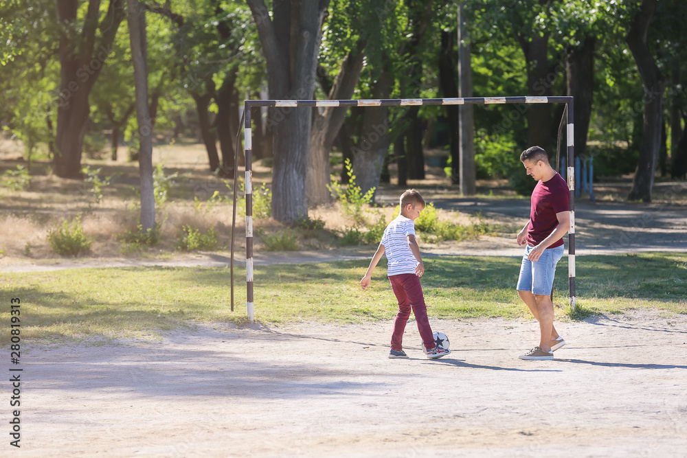 Little boy with his dad playing football on soccer pitch Little boy with his dad playing football on soccer pitch