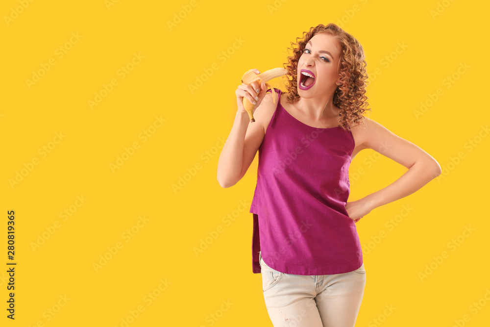 Emotional young woman eating tasty banana on color background Emotional young woman eating tasty banana on color background