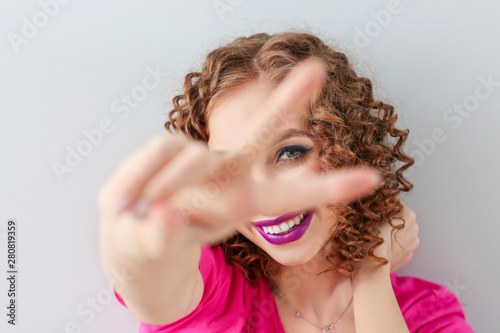 Stylish young woman showing victory gesture, closeup
