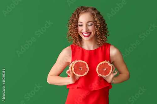 Schilderij op canvas Happy young woman with tasty grapefruit on color background