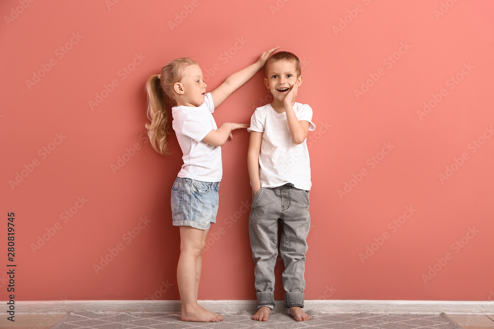 Little children measuring height near wall Little children measuring height near wall