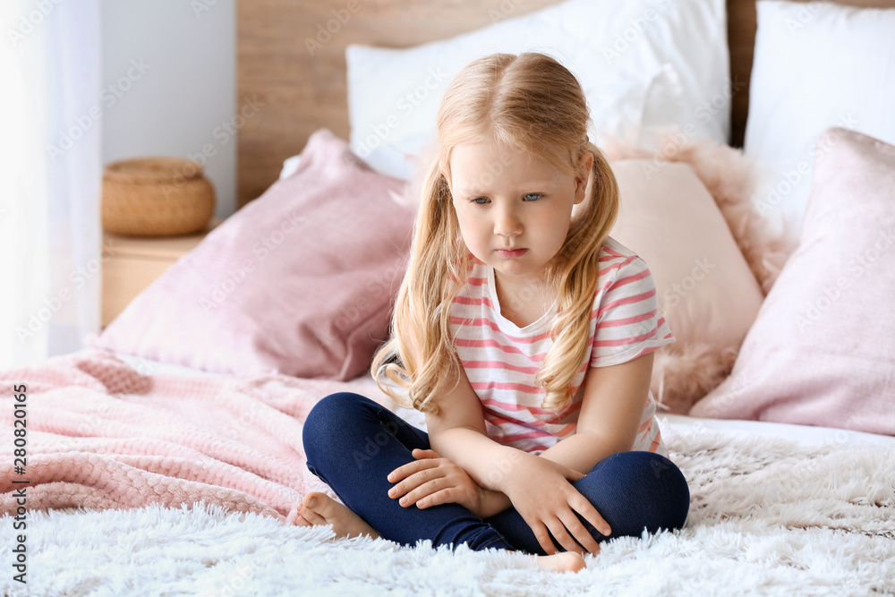 Sad little girl sitting on bed Sad little girl sitting on bed