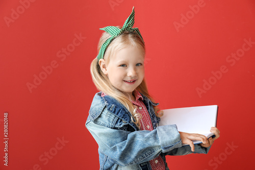 Portrait of adorable little girl reading book on color background