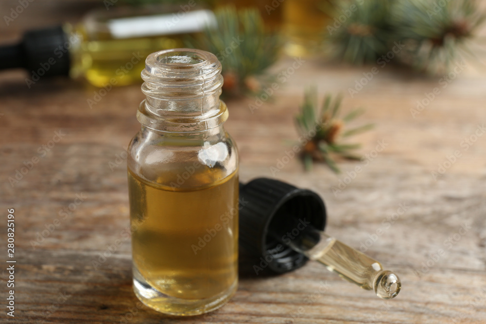 Bottle and pipette with conifer essential oil on wooden table Bottle and pipette with conifer essential oil on wooden table