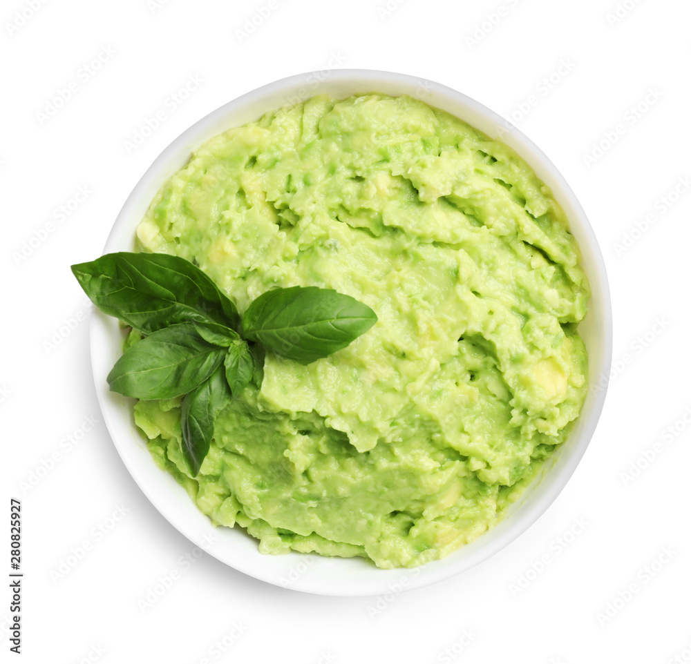 Bowl of tasty avocado sauce with basil on white background, top view