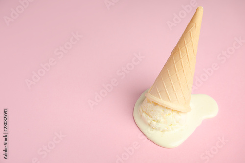 Fotografija Melted  vanilla ice cream in wafer cone on pink background
