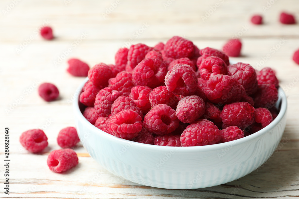Bowl of delicious fresh ripe raspberries on white wooden table, closeup view Bowl of delicious fresh ripe raspberries on white wooden table, closeup view