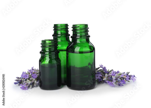 Bottles with natural lavender oil and flowers on white background