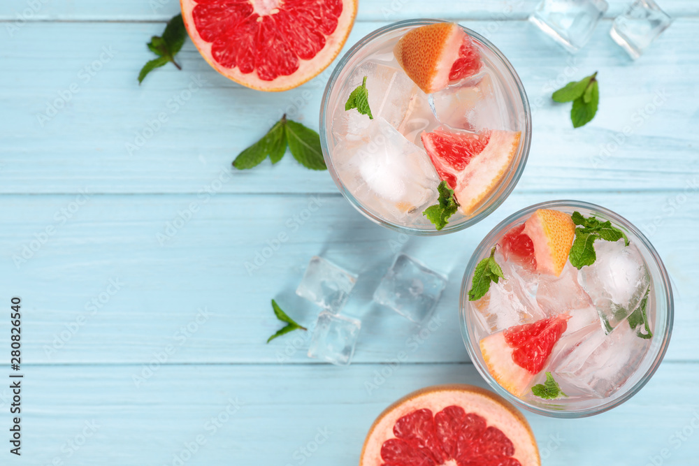 Flat lay composition of refreshing drink and grapefruits on light blue wooden table Flat lay composition of refreshing drink and grapefruits on light blue wooden table