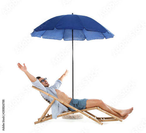 Young man on sun lounger under umbrella against white background. Beach accessories