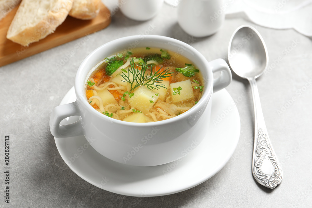 Dish of fresh homemade vegetable soup served on light grey table Dish of fresh homemade vegetable soup served on light grey table