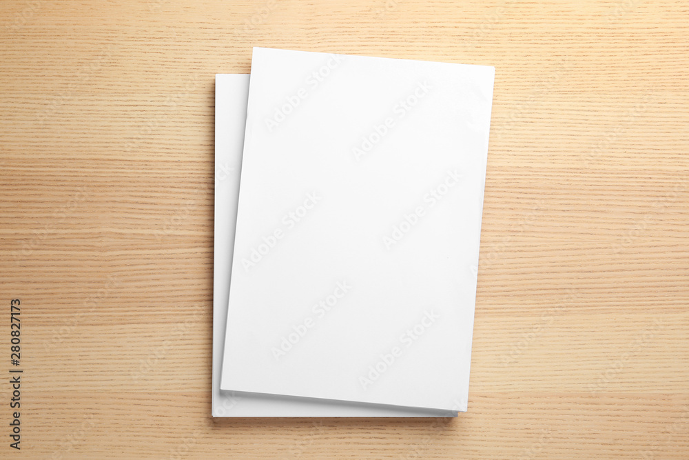 Stack of blank paper sheets for brochure on wooden background, top view. Mock up