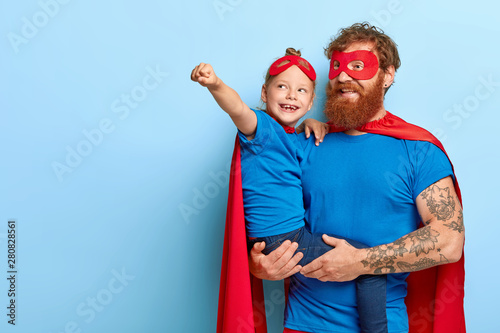Фотография Happy daughter and father have supernatural power, little girl makes flying gest