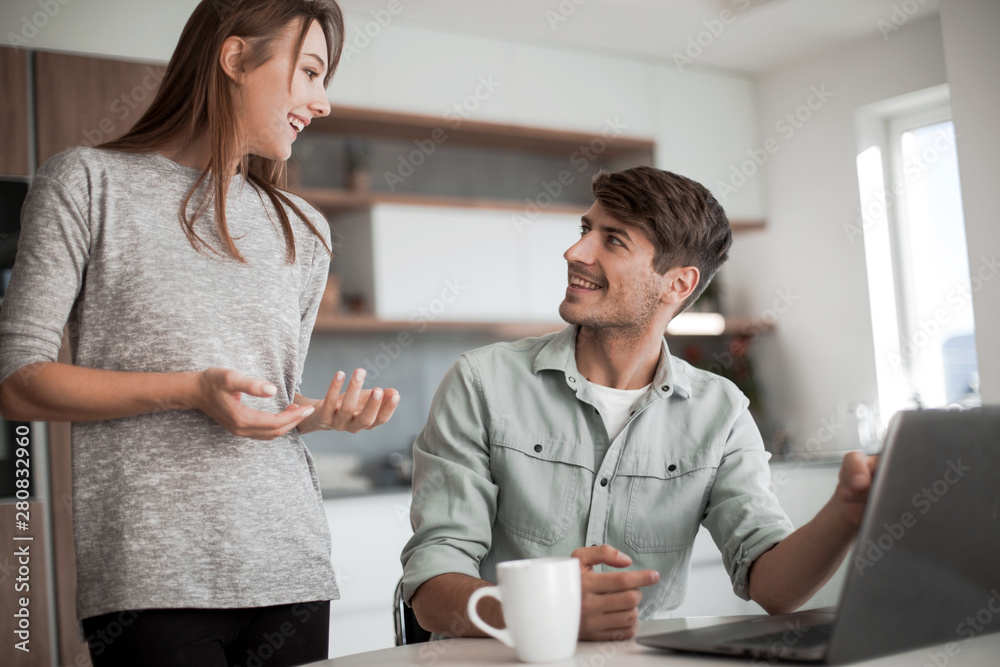Young couple looking discussing online news in the kitchen Young couple looking discussing online news in the kitchen