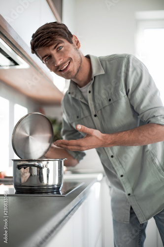 close up. a young man standing near the kitchen stove