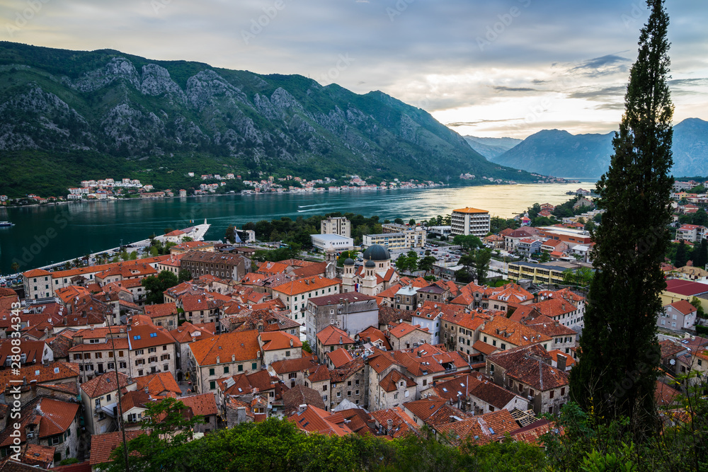 Montenegro, Aerial view over the roofs of old town of kotor bay and coastal waterside of fjord surrounded by mountains in magical evening sunset twilight