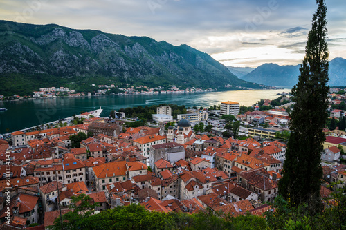 Montenegro, Aerial view over the roofs of old town of kotor bay and coastal waterside of fjord surrounded by mountains in magical evening sunset twilight