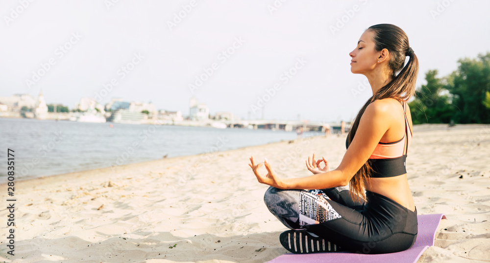 Relax inside yourself and have a rest. Side view full length photo of cute brunette young sporty woman in lotus position while she doing yoga outdoors.