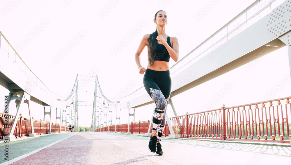 Fototapeta premium Uruchamianie młodej kobiety w sportowej odzieży na zewnątrz