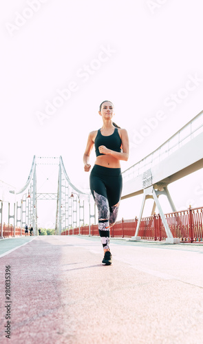 Running smiling woman in sport clothes outdoors