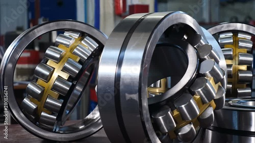 Industry and Machinery concept. Manufacture of bearings at the factory. Set of various gears and ball bearings. Unidentified worker in blue uniform passing by. spare parts at warehouse. Close up. 4k