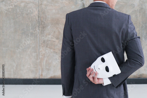 Businessman holding white mask in his hand dishonest cheating agreement.Faking and betray business partnership concept photo