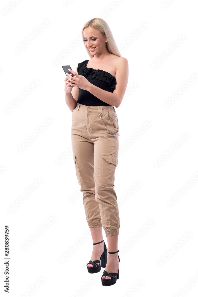 Happy smiling blonde stylish woman using mobile phone typing message. Full body isolated on white background. Happy smiling blonde stylish woman using mobile phone typing message. Full body isolated on white background.