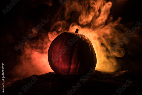 Halloween theme with pumpkin against smoky dark background. Empty space for text photo