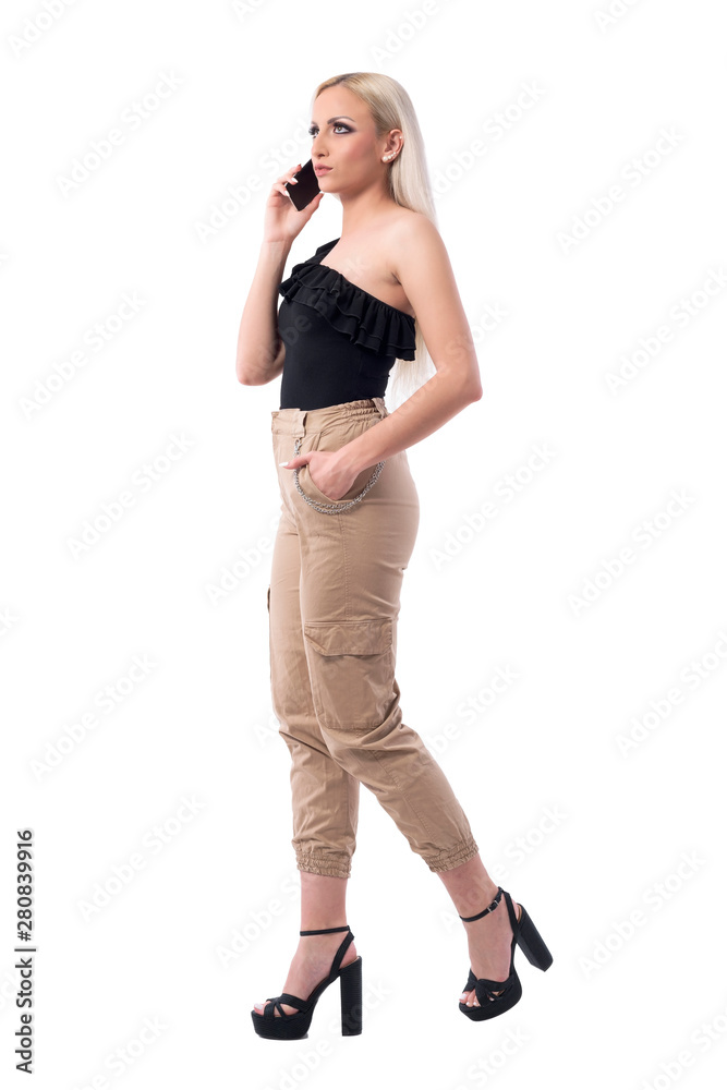 Fototapeta premium Serious attitude woman walking and talking on cellphone looking up. Side view. Full body isolated on white background. 