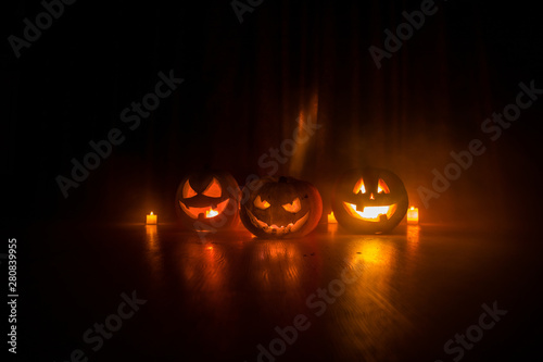 Halloween pumpkin head jack o lantern with glowing candles on background. Pumpkins on wooden floor