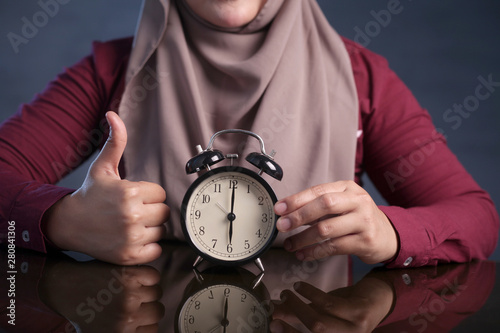 Muslim Woman Holding Clock Pointing at Six O'Clock