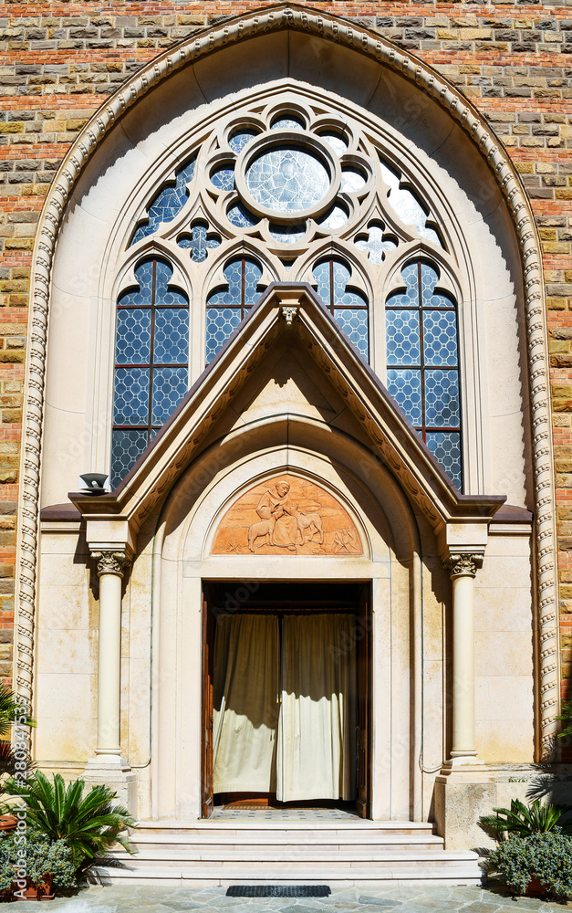 Diano Marina, Imperia / Italy - June 20 2019: Entrance portal of the Church of the Sacred Heart (Chiesa del Sacro Cuore in Italian), dating from late 19th to early 20th century, in neo-Gothic style