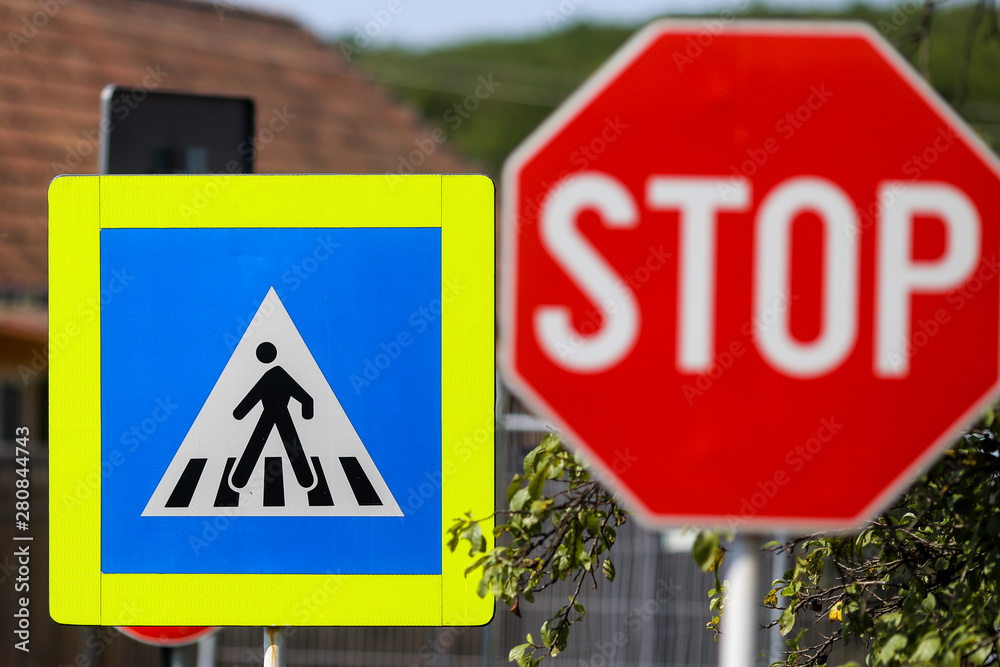 Stop and pedestrian crossing sign one next to another on a street Stop and pedestrian crossing sign one next to another on a street