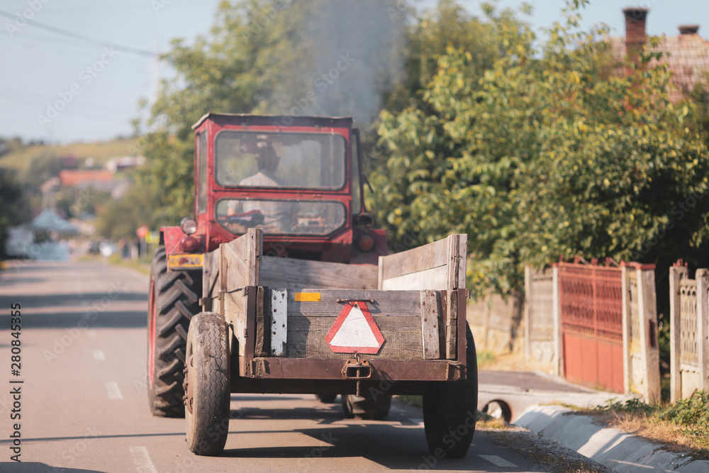 Old tractor on the streets of a village in rural Romania with plenty of vegetation around