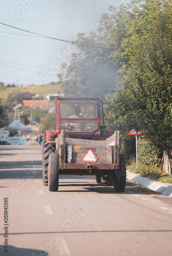 Old tractor on the streets of a village in rural Romania with plenty of vegetation around
