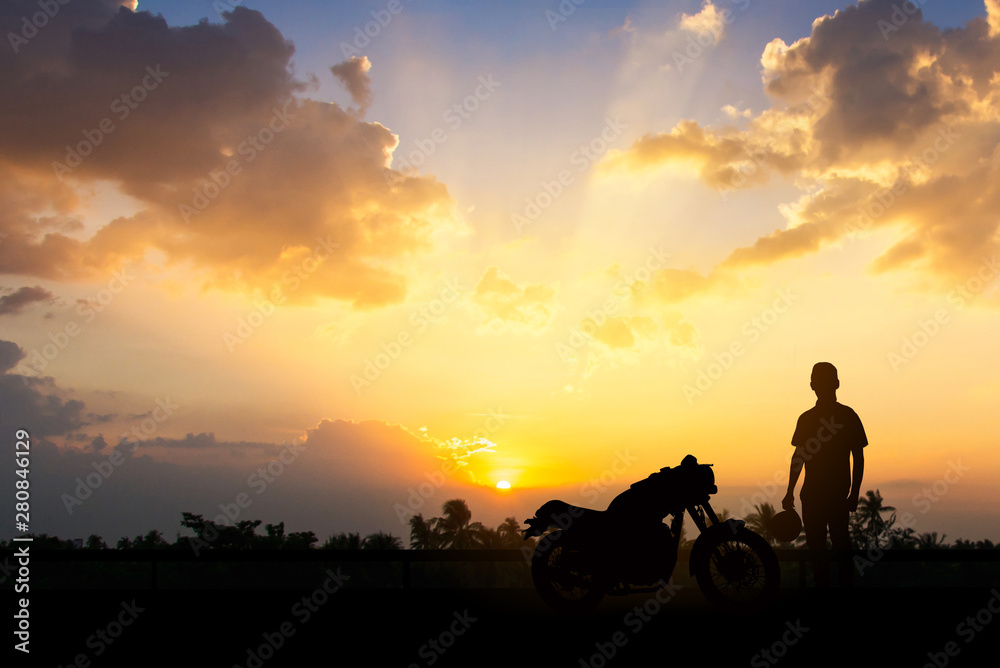 Silhouette of Back biker or rider,motorbike parking with sunset background .Traveller man standing and holding helmet beside motorcycle.Trip and lifestyle of motorbike concept,copy space. Silhouette of Back biker or rider,motorbike parking with sunset background .Traveller man standing and holding helmet beside motorcycle.Trip and lifestyle of motorbike concept,copy space.
