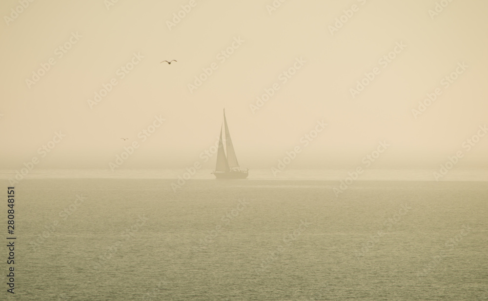 sailboat in summer fog at noon on the beach of Näset Gothenburg Sweden