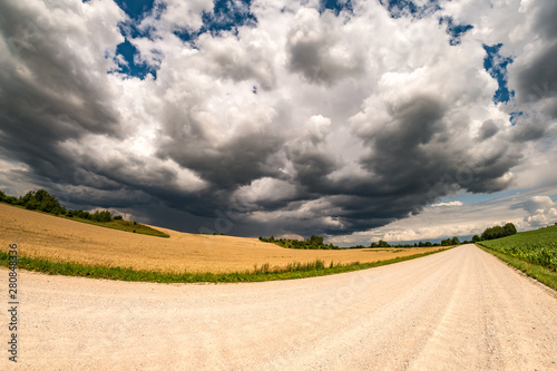 hdr panorama on asphalt road among fields in evening with awesome black clouds before storm