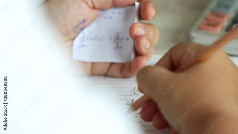 Student using formula math sheet to cheat on test. Hand of university student holding pencil doing math question in examination and cheating in test with answer piece of paper in hand.