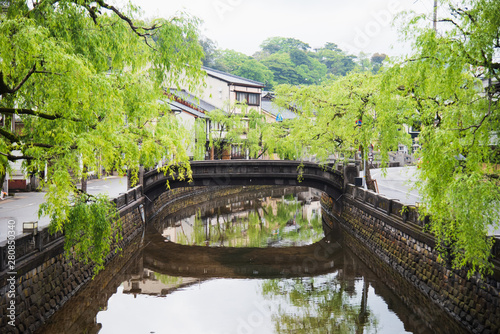 Canal view spring season in Kinosaki Onsen village, Toyooka City, Hyogo, Japan. Landscape city view. Tree beside canal with reflect in water near the bridge. Japan traveler trip.