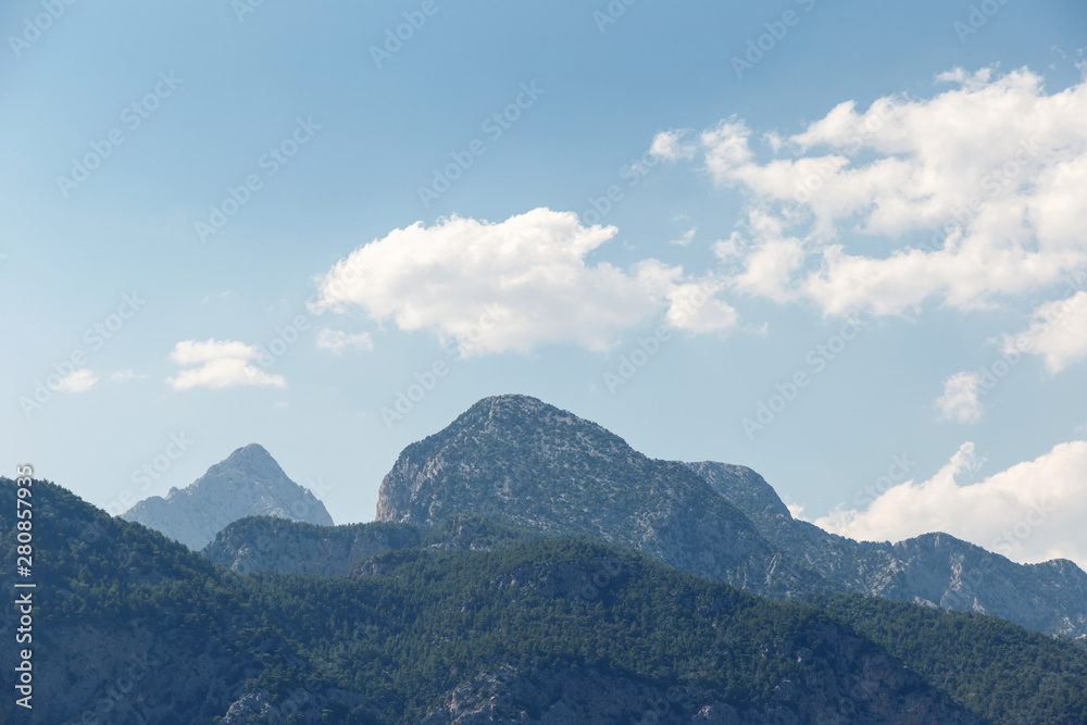 Beautiful landscape in the mountains. Lovely view of the Taurus Mountains against the blue sky and clouds. Soft sunlight falls on the mountain tops. Kemer, Turkey. Postcard view