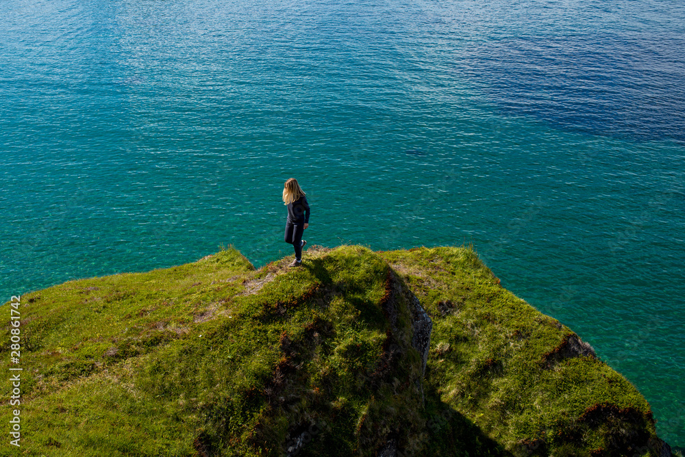 Obraz premium Happy woman enjoy scenic view of the blue ocean and mountains. Harmony with beautiful nature, relaxation lifestyle. Travel, adventure. Sense of freedom. Explore North Norway. Summer in Scandinavia