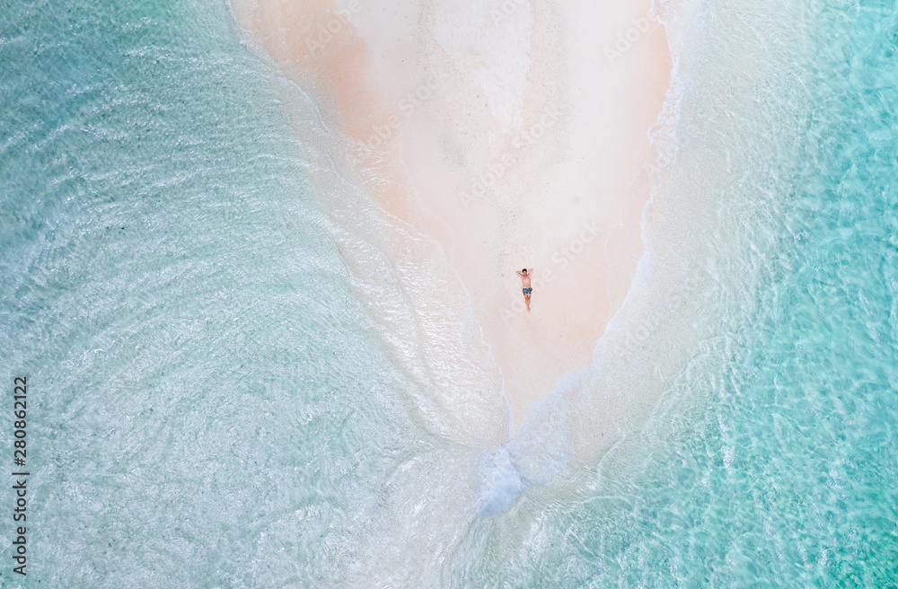 Naked island view from the sky. Man relaxing taking sunbath on the beach.shot taken with drone above the beautiful scene. concept about travel, nature, and marine landscapes