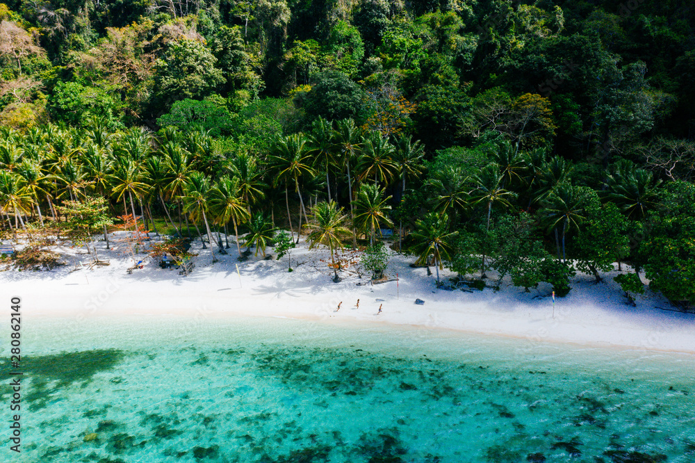 Enjoying the time at the beach. People walking on the white sand, with tropical jungle in the background. Concept about traveling and nature Enjoying the time at the beach. People walking on the white sand, with tropical jungle in the background. Concept about traveling and nature